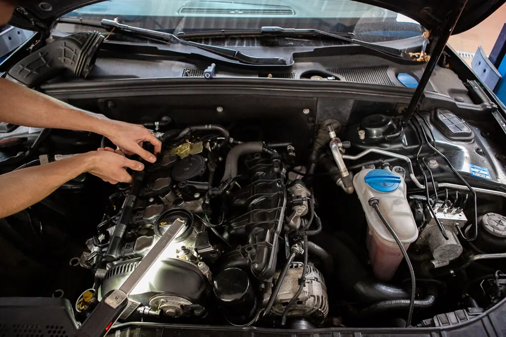 Mechaniker arbeitet im Motorraum eines Autos in der Werkstatt von WID Autohaus
